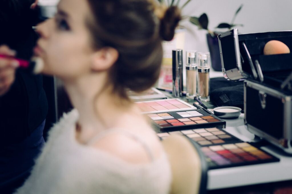 A woman receiving professional makeup in a studio with various cosmetics in focus.