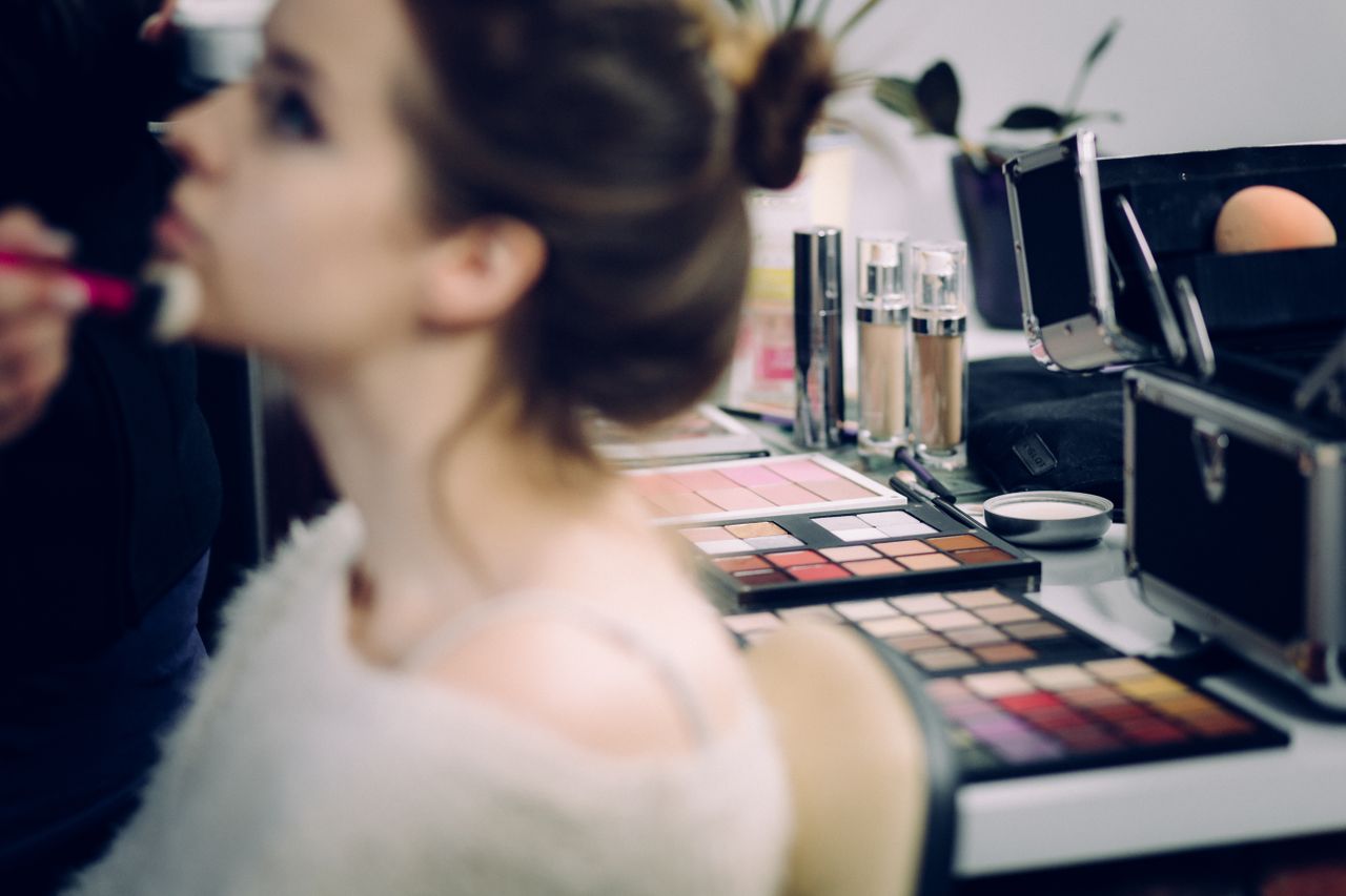 A woman receiving professional makeup in a studio with various cosmetics in focus.